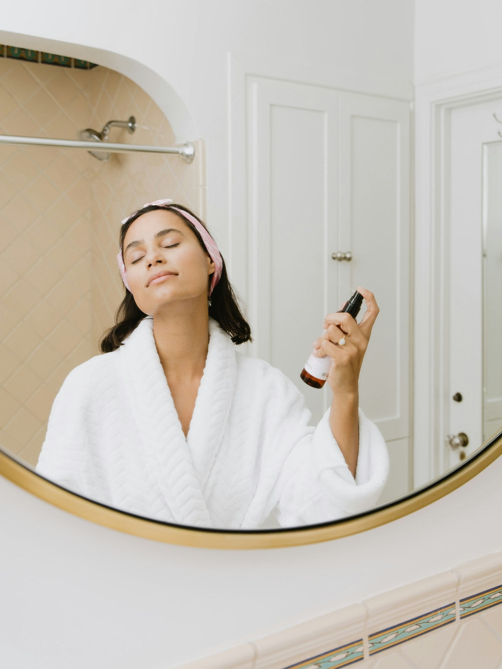 Frau im Bademantel bei ihrer koreanischen Skincare-Routine im Badezimmer