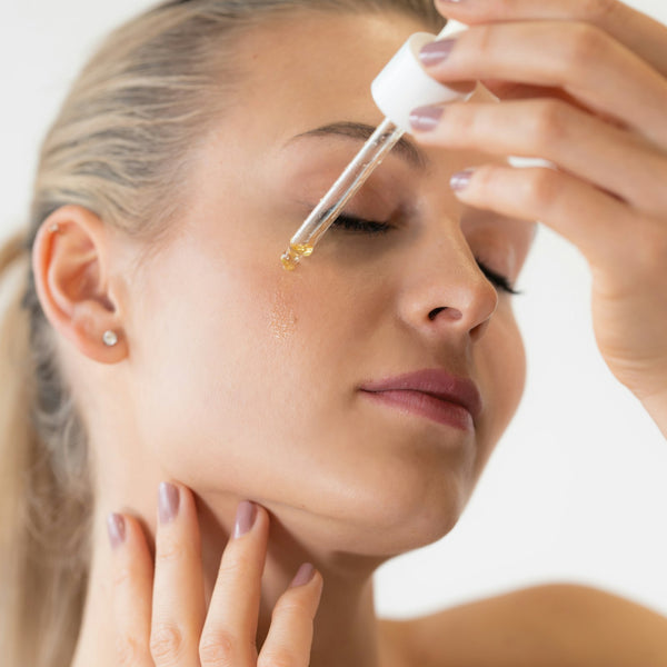 Frau trägt PDRN Serum mit einer Pipette auf die Gesichtshaut auf